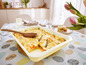 Un plat de gratin avec des asperges, des carottes et du fromage sur une table avec des œufs de Pâques.