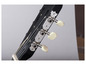 La tête d'une guitare acoustique noire avec des mécaniques argentées.