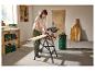 Femme utilise une scie circulaire et un aspirateur industriel pour couper du bois dans un atelier.