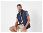 Un homme portant un gilet matelassé bleu marine et un t-shirt à rayures.