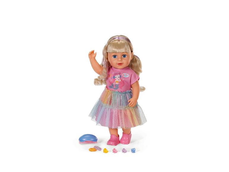 Poupée BABY born aux cheveux blonds, t-shirt rose, jupe arc-en-ciel et accessoires.