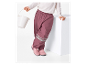 Une fillette portant un pantalon imperméable rose et des bottes roses, tenant un seau blanc.