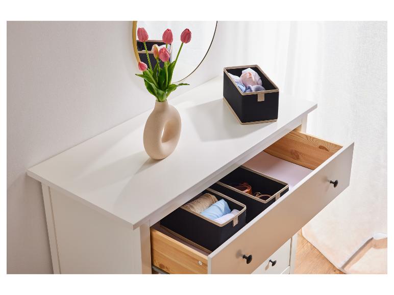 Une commode blanche avec un tiroir ouvert, contenant deux boîtes de rangement noires avec un bord beige.
