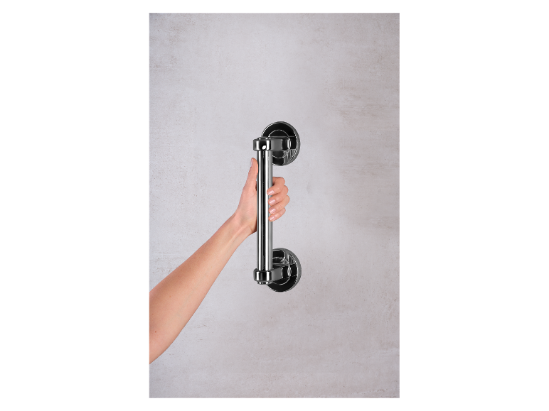 Une main tient une poignée en métal chromé fixée au mur.
