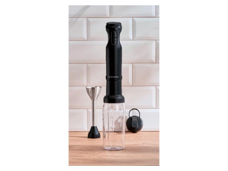 Mixeur plongeant SilverCrest noir avec verre doseur et fouet sur un comptoir en bois.