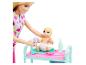Poupée Barbie et coffret de jeu avec un bébé sur une table à langer.