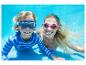 Deux personnes en lunettes de natation et maillots de bain sous l'eau, souriant à la caméra.