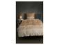 Parure de lit beige à motif géométrique sur un lit avec lampe de chevet et table.