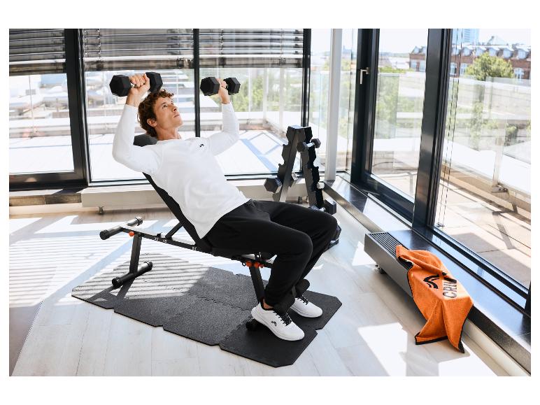 Homme s'entraîne avec des haltères sur un tapis de protection CRIVIT.