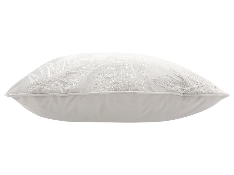 Coussin décoratif blanc avec motif de feuilles brodé.