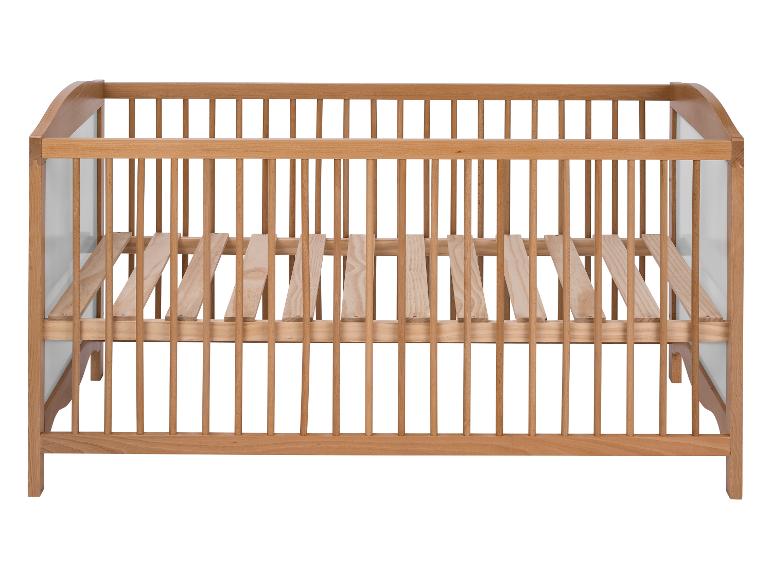 Un lit bébé en bois avec des barreaux.