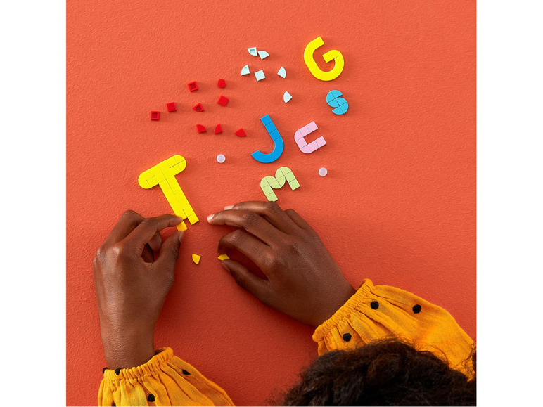 Une personne construit des lettres avec des blocs LEGO colorés.