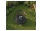 Enfant sur un trampoline avec filet de sécurité dans un jardin verdoyant fleuri.