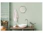 Salle de bain avec lavabo, miroir, serviette et plantes dans une teinte verte apaisante.