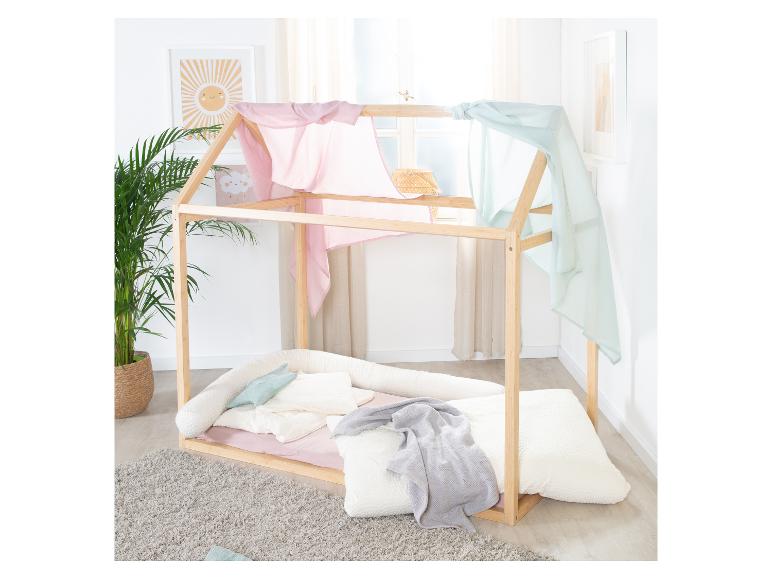 Lit cabane en bois avec baldaquin rose et bleu, plantes et art mural.