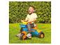 Un enfant fait du tricycle Hot Wheels dans le jardin.