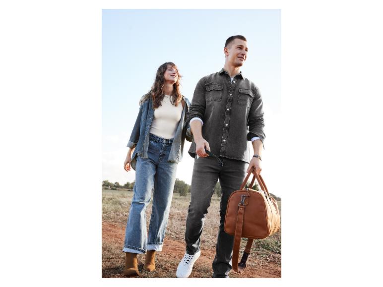 Un couple marche avec un sac de voyage en cuir et des vêtements en jean.