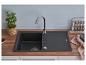 Évier noir avec robinet, herbes, épices et fraises sur un plan de travail en bois.