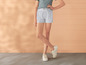 Un mannequin porte un short gris et des baskets blanches.