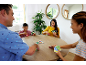 Famille jouant à un jeu de cartes autour d'une table en bois, souriante et engagée.