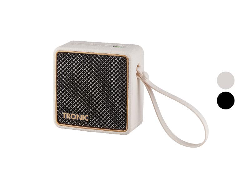 Enceinte portable blanche avec grille métallique et dragonne.