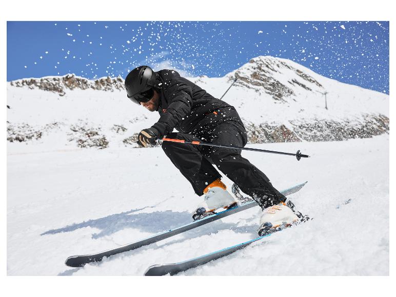Homme skiant sur une montagne enneigée, portant une veste, un pantalon et un casque de ski noirs.
