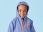 Un enfant porte un imperméable bleu avec un motif arc-en-ciel.