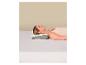 Femme allongée sur le dos sur un matelas blanc avec un oreiller ergonomique gris et blanc.