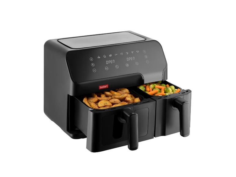 Friteuse à air noire Bodum avec deux tiroirs, remplis de frites et de légumes.