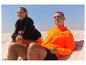 Vêtements de sport : veste orange et sweat noir, sur la plage.