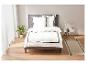 Draps blancs avec bordure noire sur un cadre de lit gris.