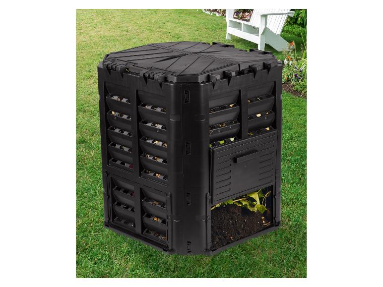 Composteur noir dans un jardin avec un rabat inférieur ouvert, révélant de la terre et des feuilles compostées.