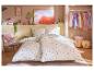 Parure de lit fraise et rayée dans une chambre avec armoire et fauteuil.