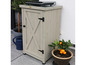 Une armoire de rangement en bois avec une porte à panneaux, un gril et des plantes sur une terrasse.