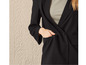 Une femme portant un blazer noir sur un haut beige.