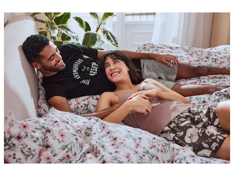 Couple détendu dans un lit avec linge de lit fleuri et pyjamas assortis.