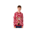 Un adolescent souriant portant un pull de Noël rouge avec un motif de renne