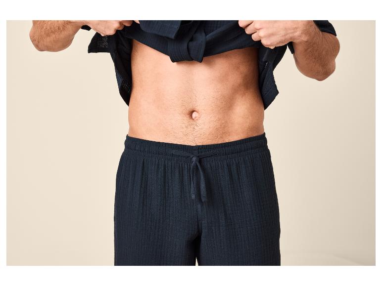 Homme en pyjama bleu marine, montrant son ventre.