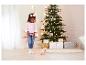 Une fillette joue avec un chiot interactif en peluche devant le sapin de Noël.