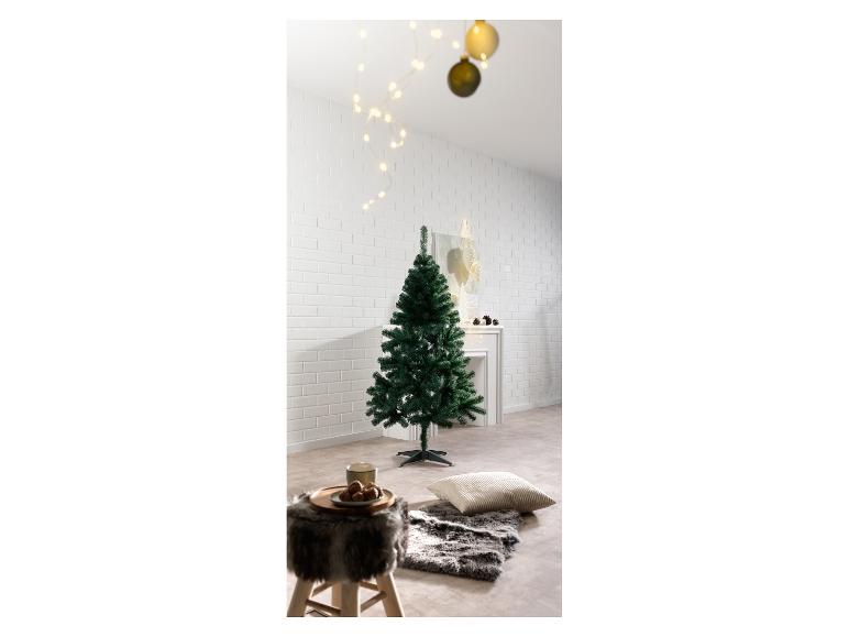 Sapin de Noël artificiel dans une pièce décorée de lumières et d'un tapis en fourrure.