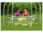 Deux filles dans une piscine gonflable avec un motif de feuilles de palmier et un parasol vert.