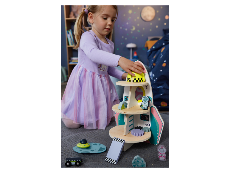 Une fillette joue avec un jouet fusée en bois.