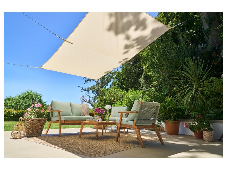 Ensemble de mobilier d'extérieur avec canapé, fauteuils, table basse et voile d'ombrage sur une terrasse.