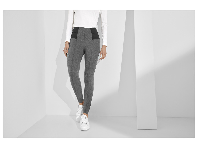 Un mannequin porte un legging gris avec des baskets blanches.