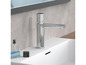 Un robinet de lavabo chromé avec un lavabo et un flacon de parfum.