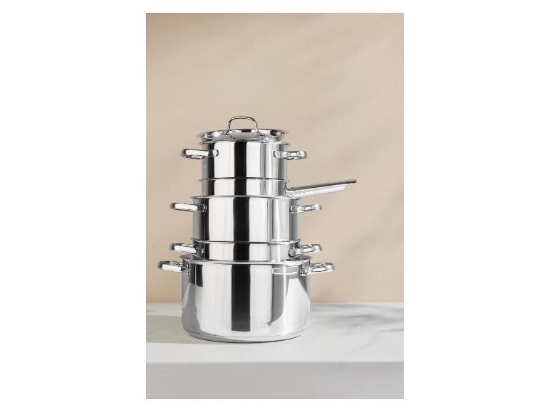 Ensemble de casseroles en acier inoxydable empilées sur un comptoir blanc.