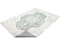 Tapis clair avec motif floral bleu foncé et bord plié montrant le dessous.