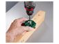 Une main utilise une perceuse Parkside pour percer un trou dans une poutre en bois à l'aide d'un gabarit de perçage.