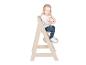 Petite fille souriante assise dans une chaise haute en bois beige.