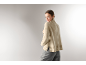 Femme de dos portant un pull à col roulé beige et un pantalon gris.
